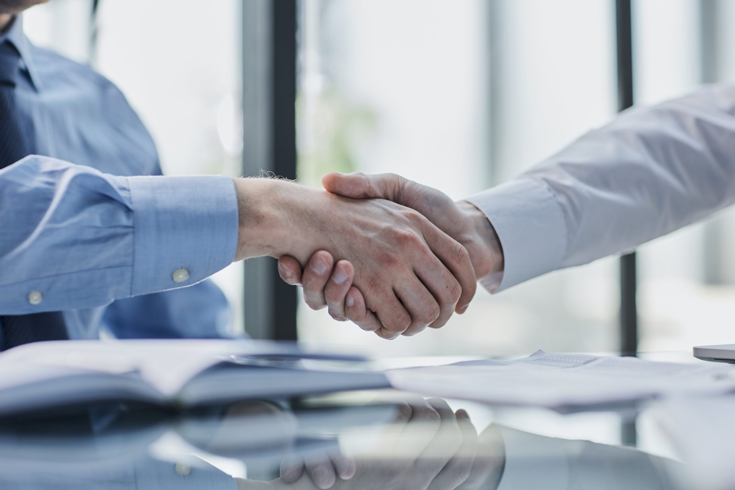 Professional handshake across a conference table, symbolizing a business agreement or partnership.