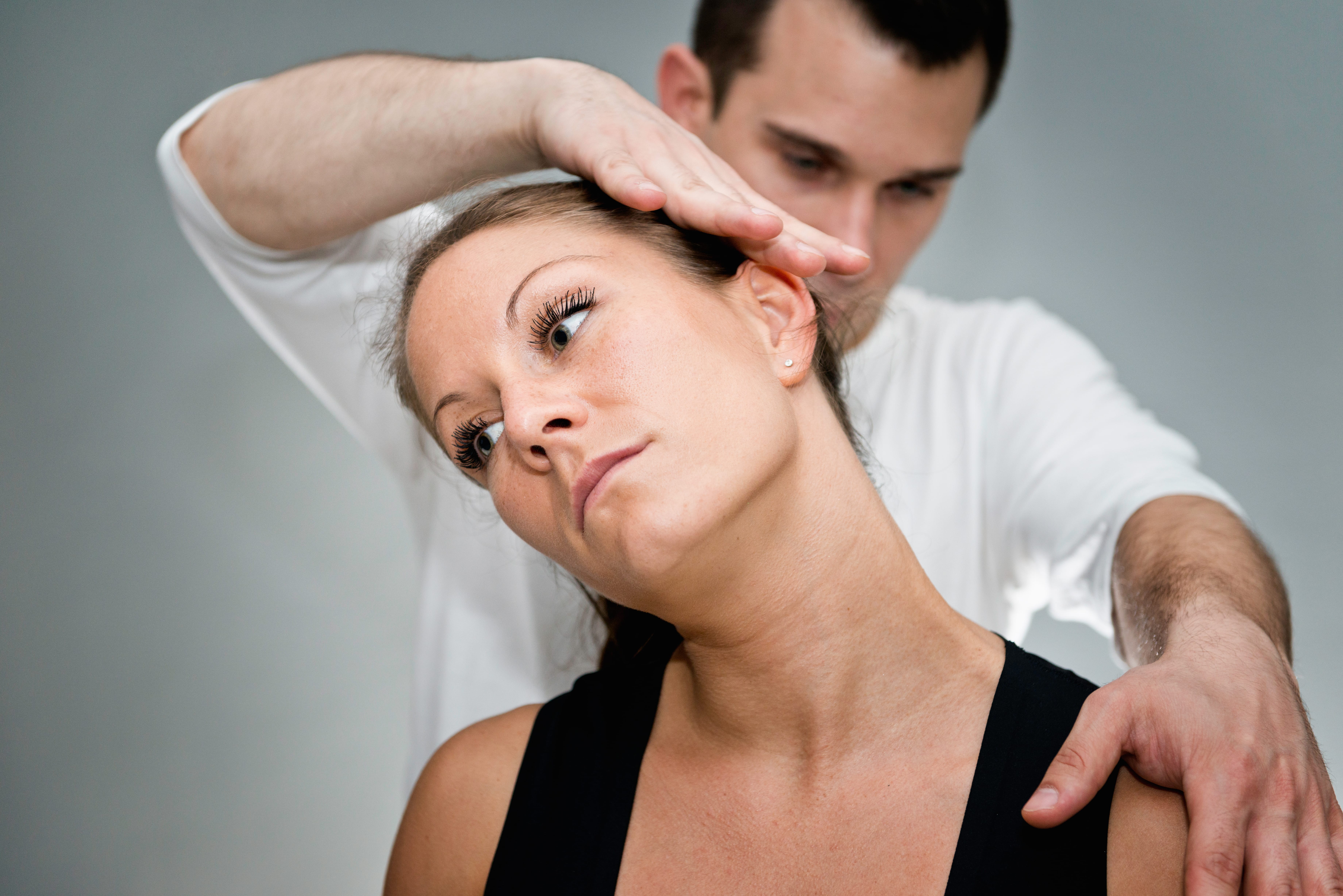 Chiropractor performs a neck adjustment on a patient during a treatment session in a chiropractic office.