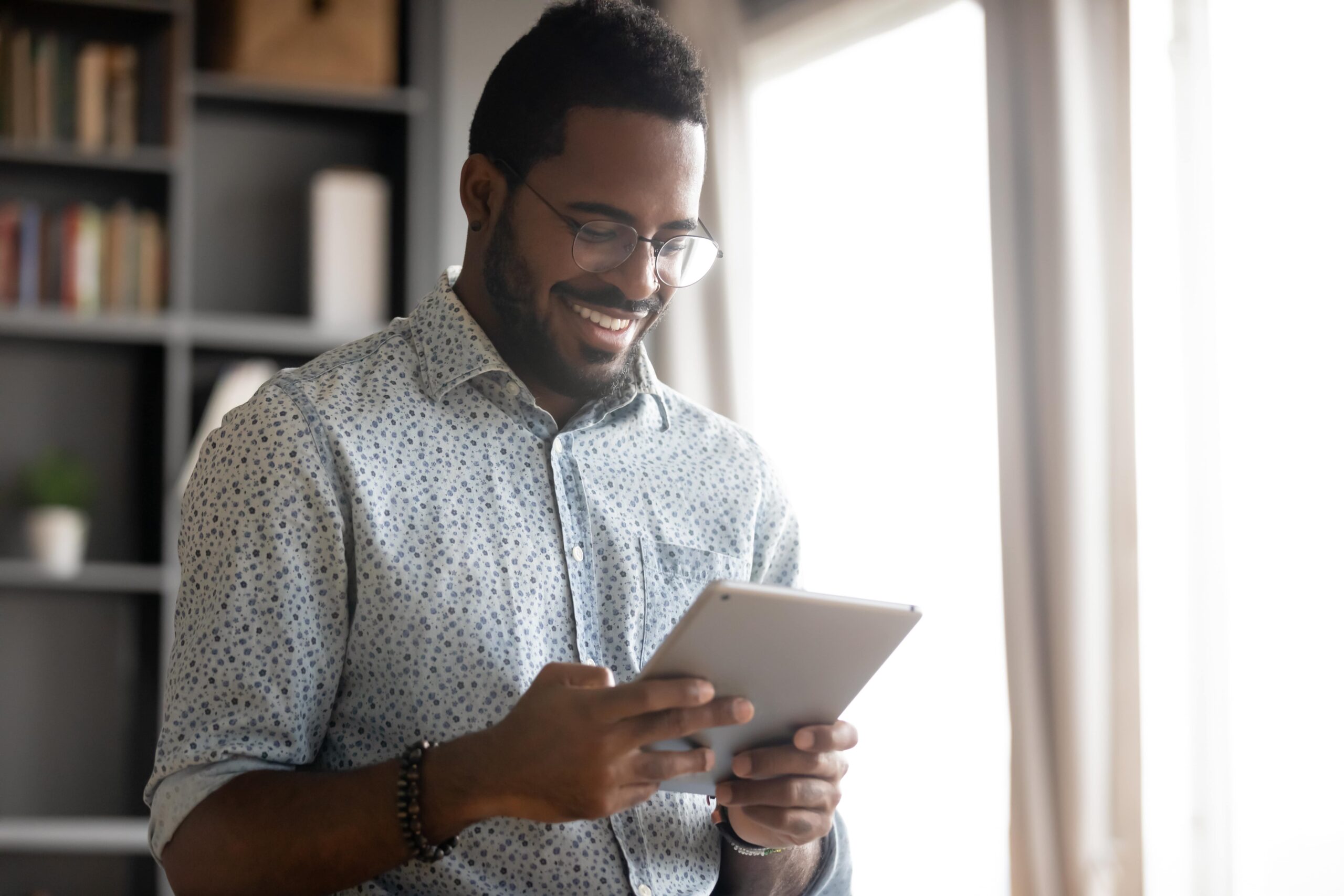 Man smiling while looking at a tablet.