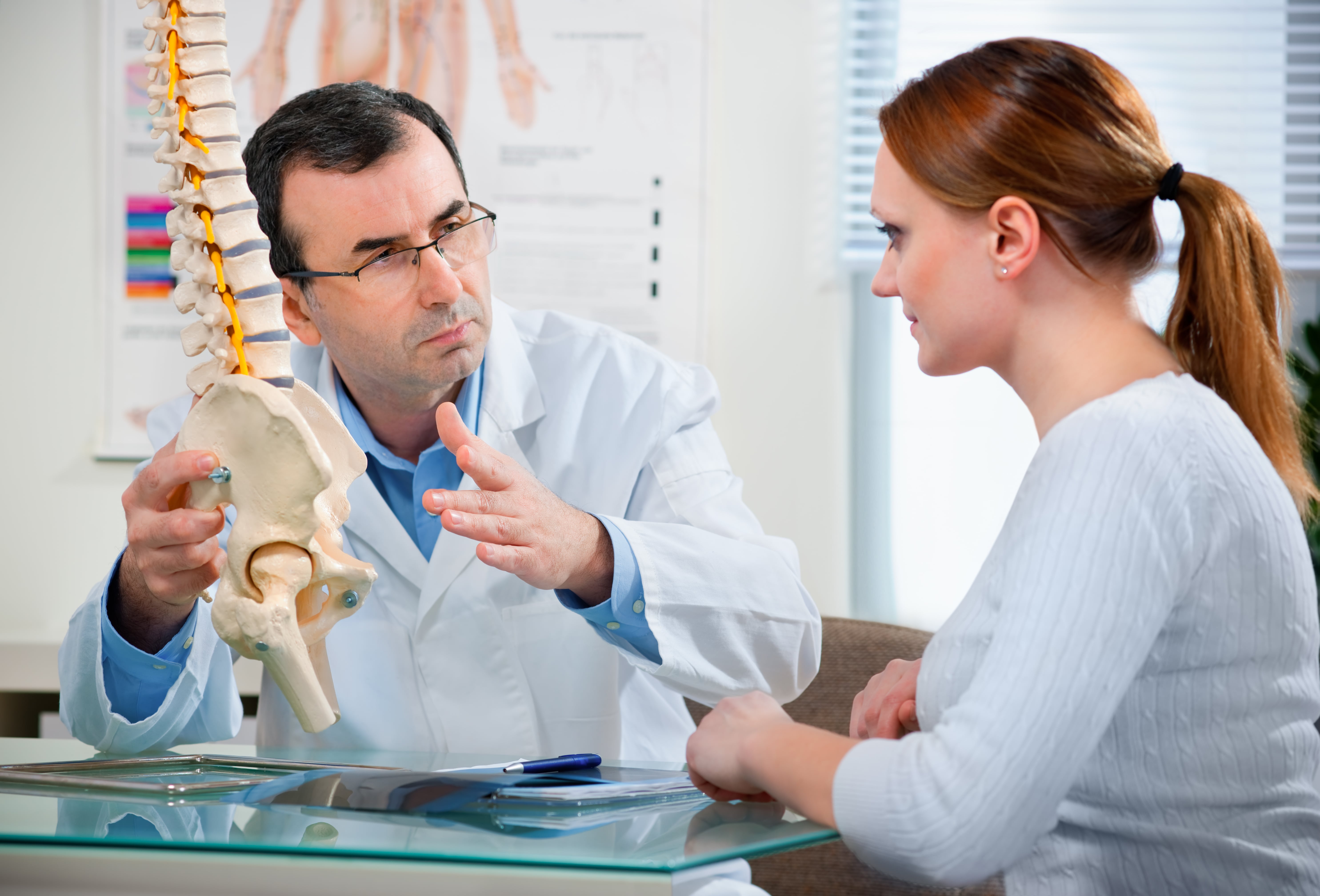 Chiropractor pointing to spine model.