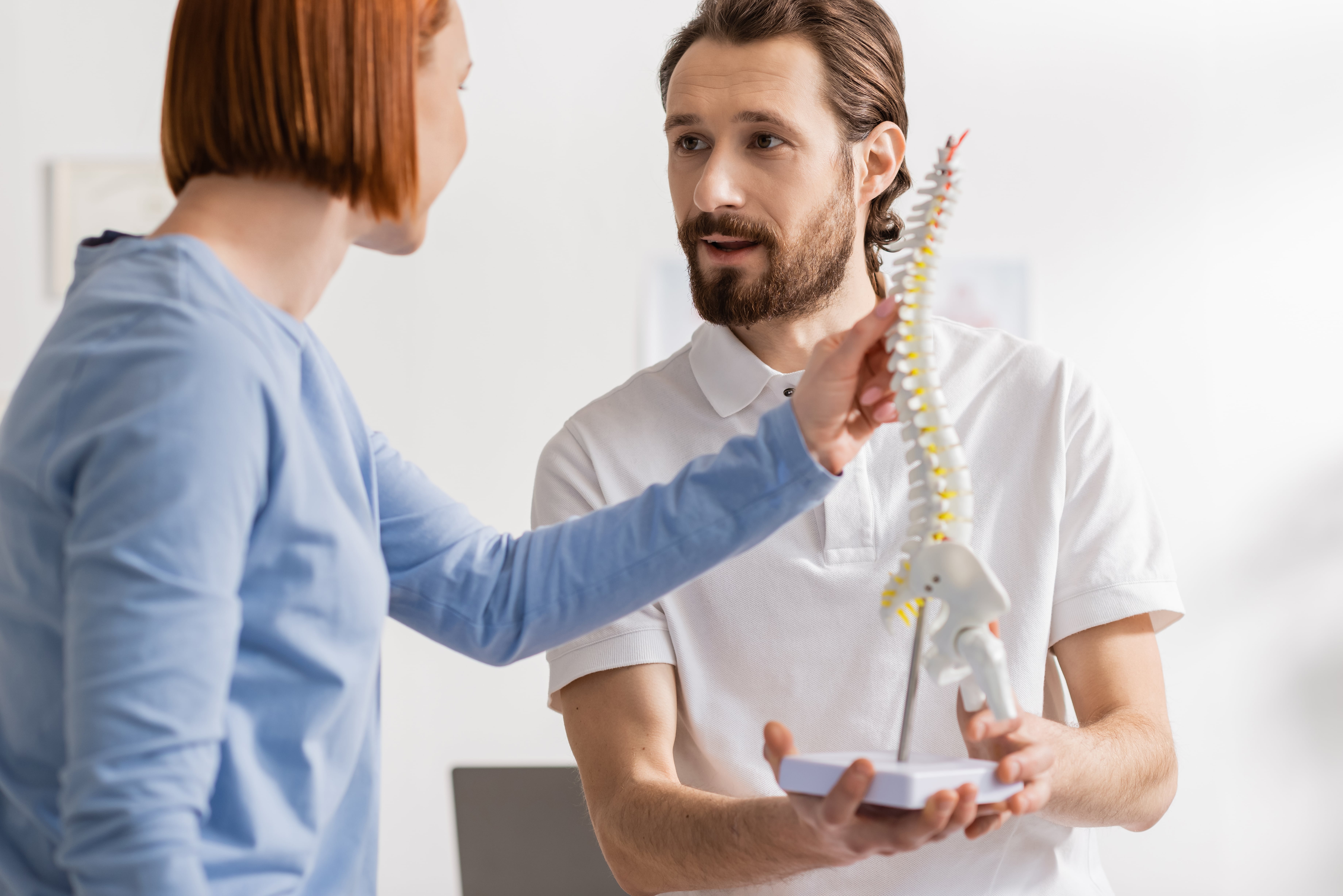 Chiropractor showing spine model to patient.