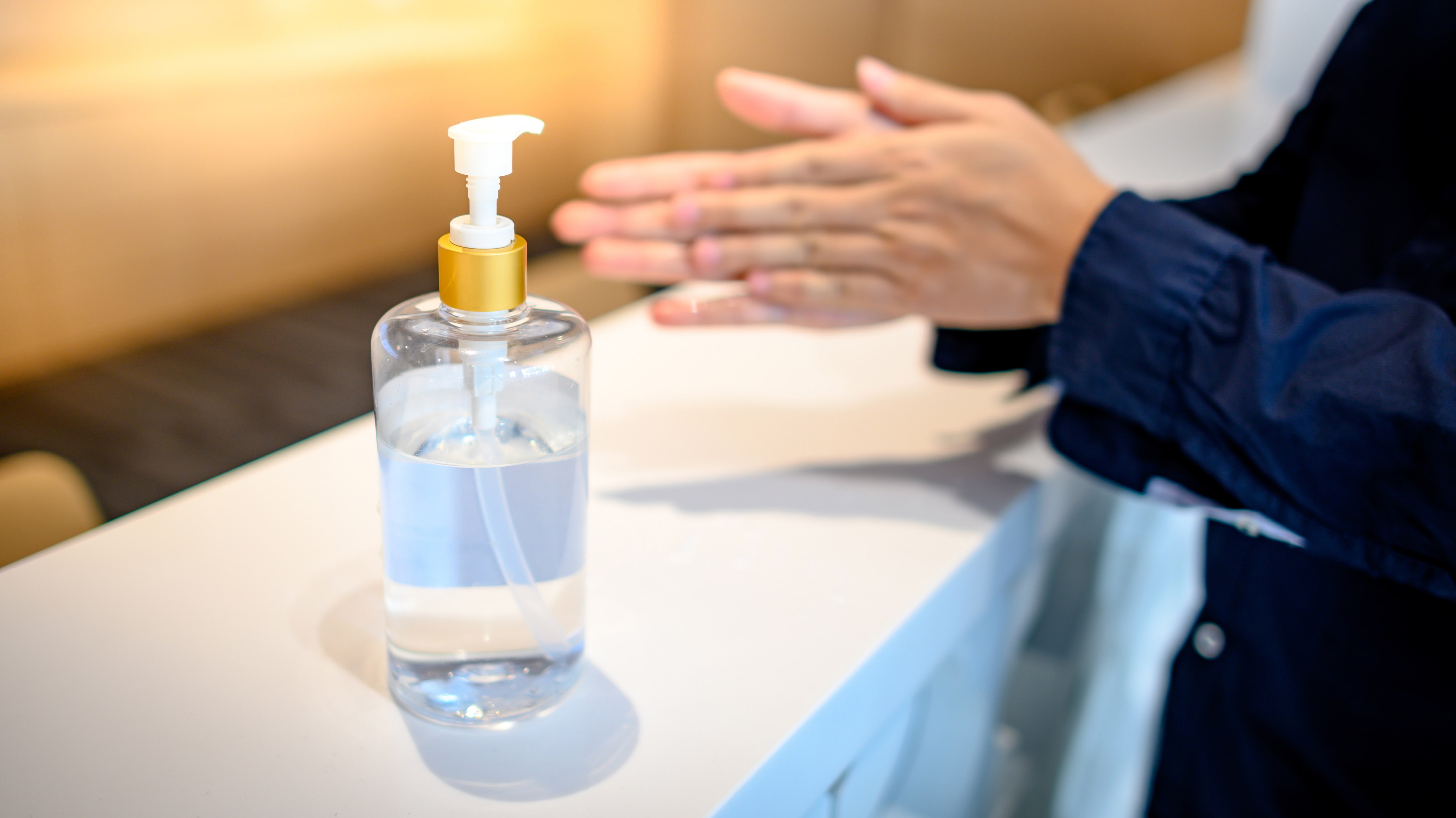 Person using hand sanitizer at reception desk.