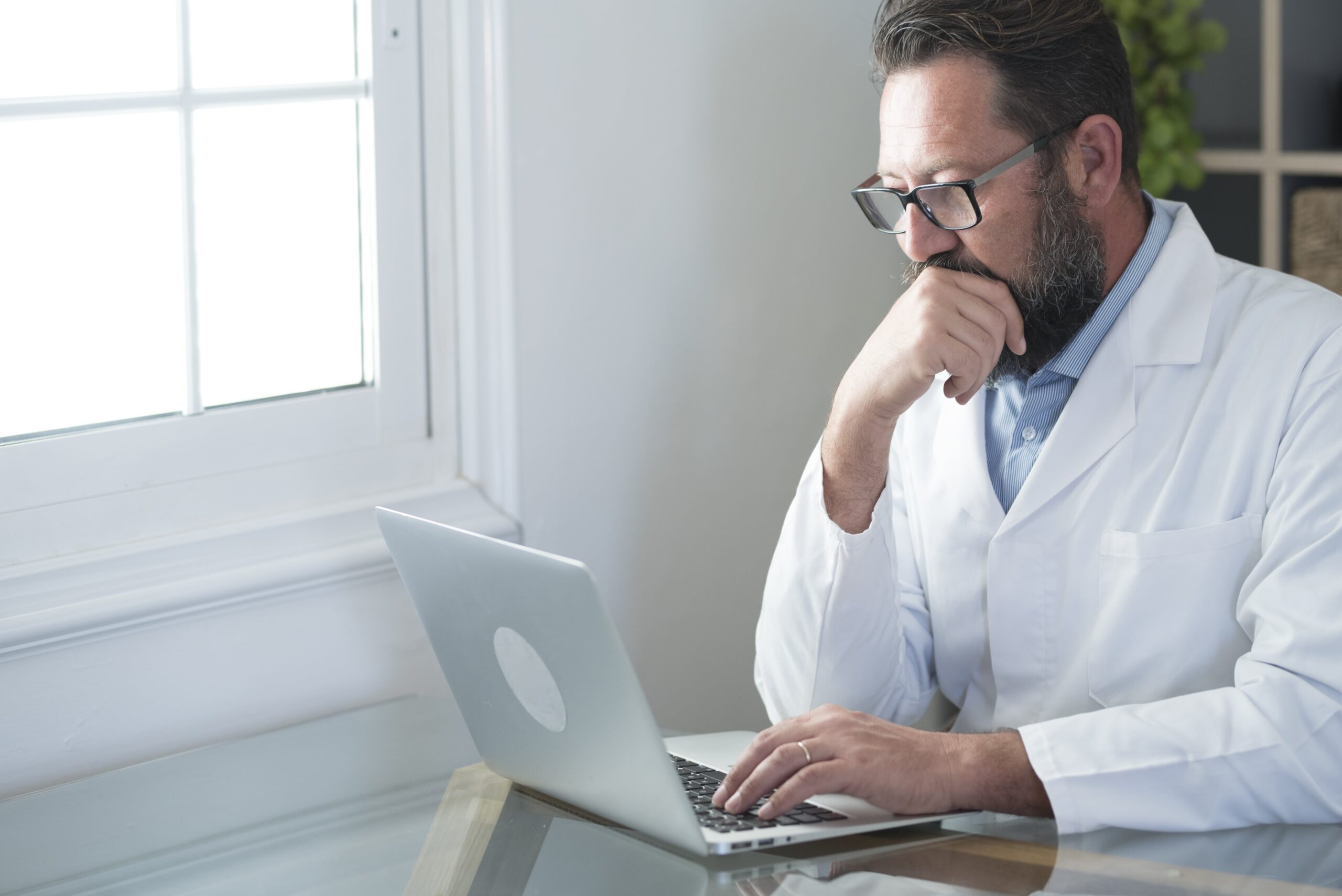 Chiropractor sitting at a desk working on a laptop.