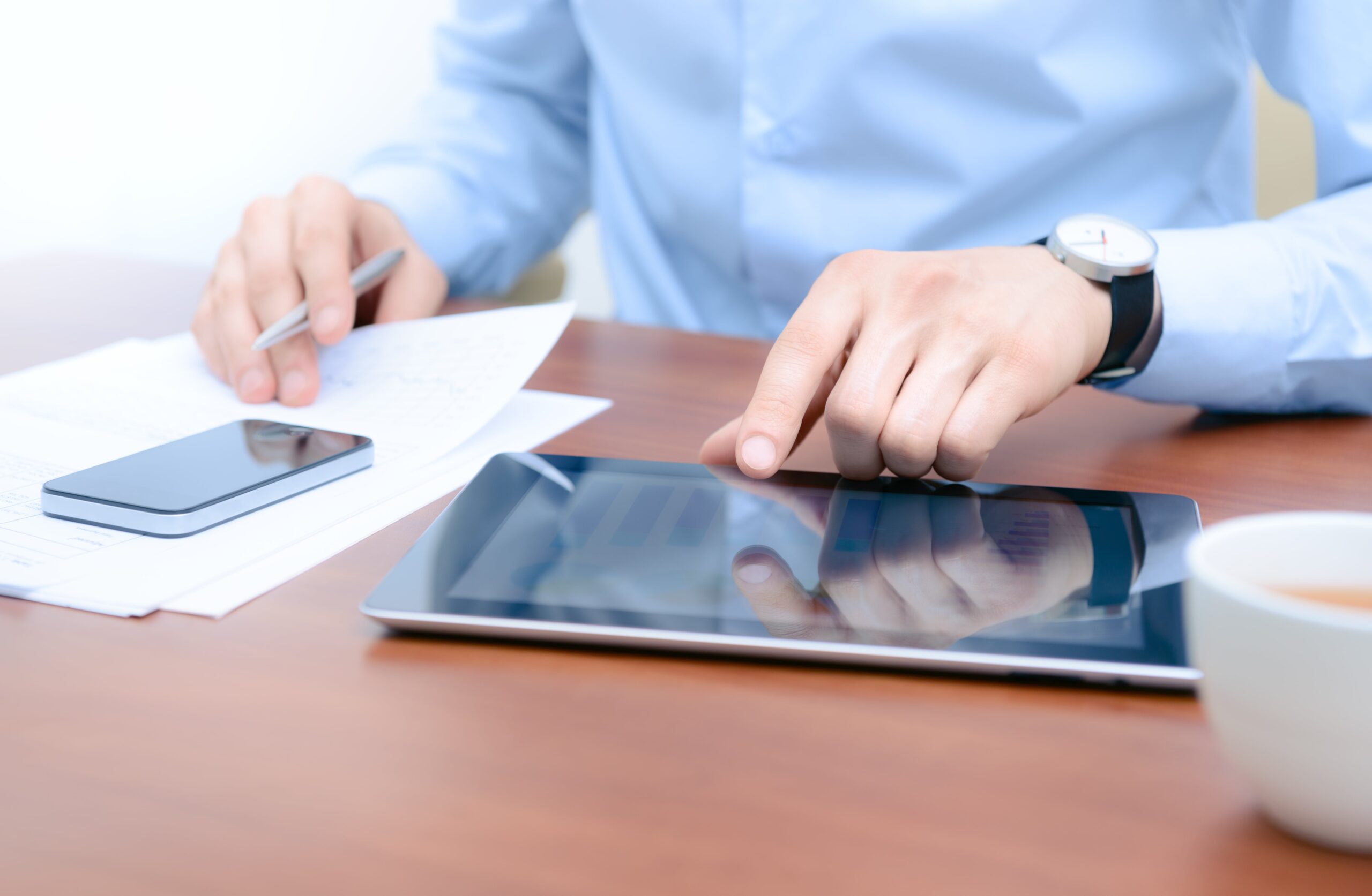 Chiropractor working at desk using tablet and phone.