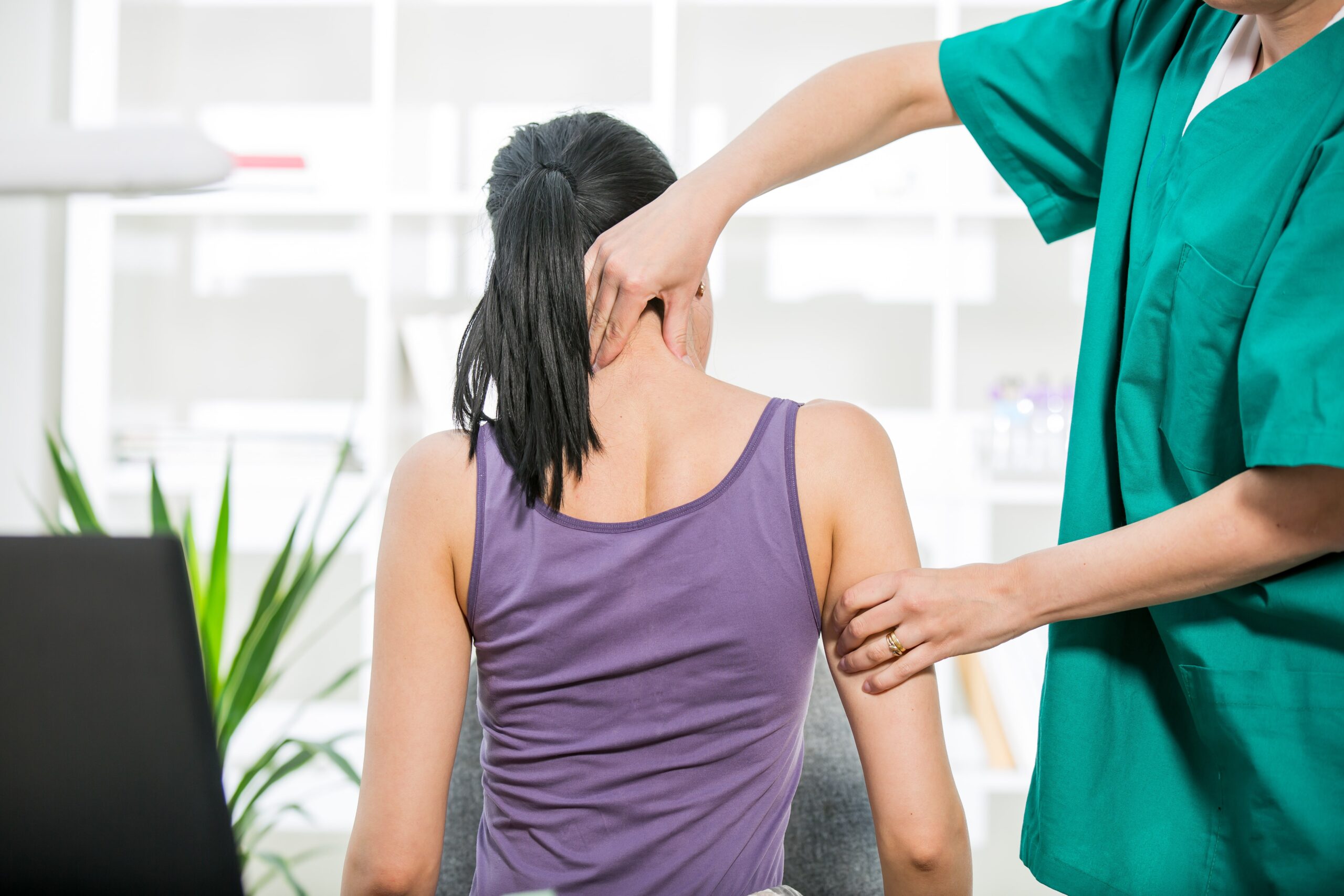 Chiropractor adjusting neck muscles of patient.