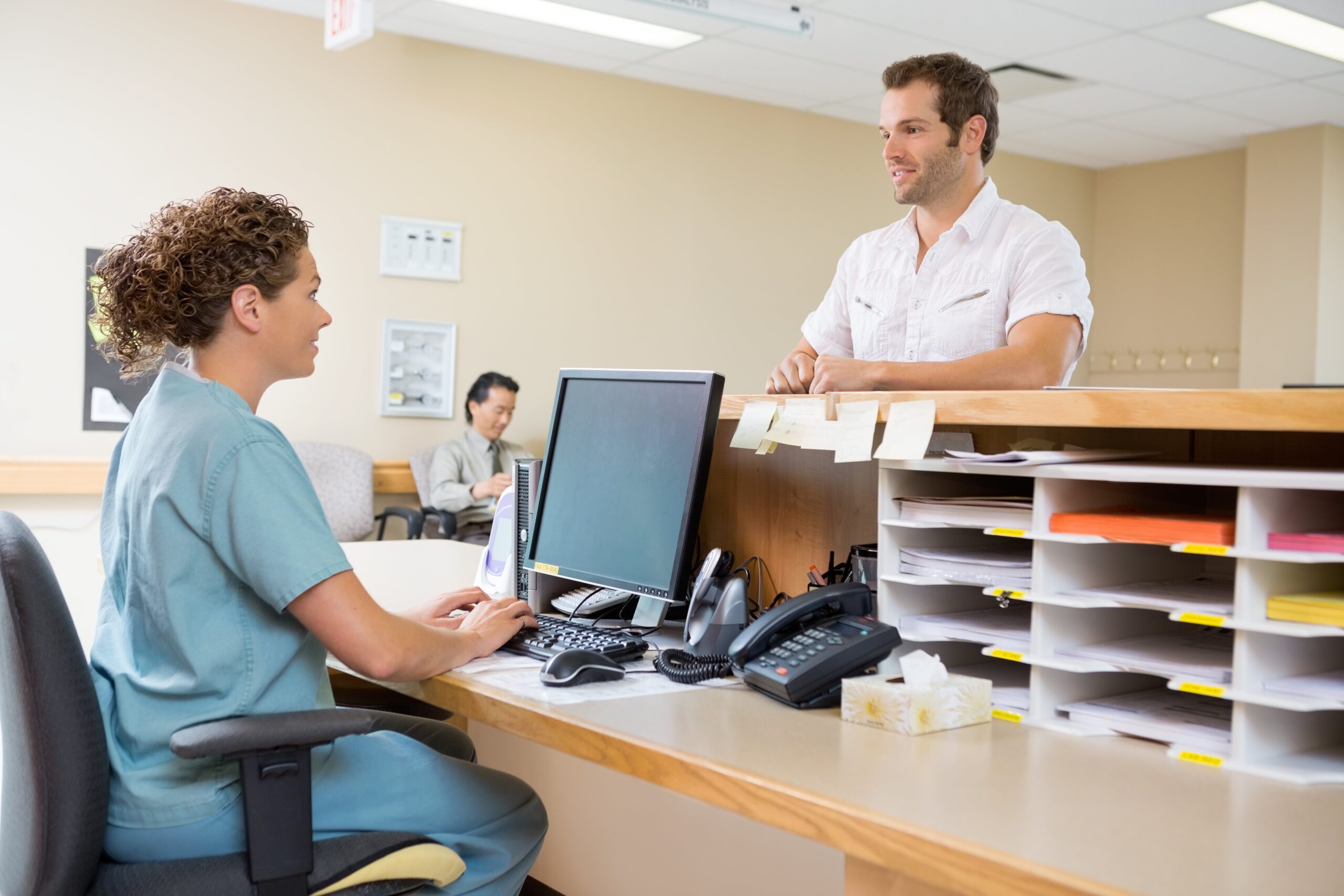 Patient standing at front desk in chiropractors office.