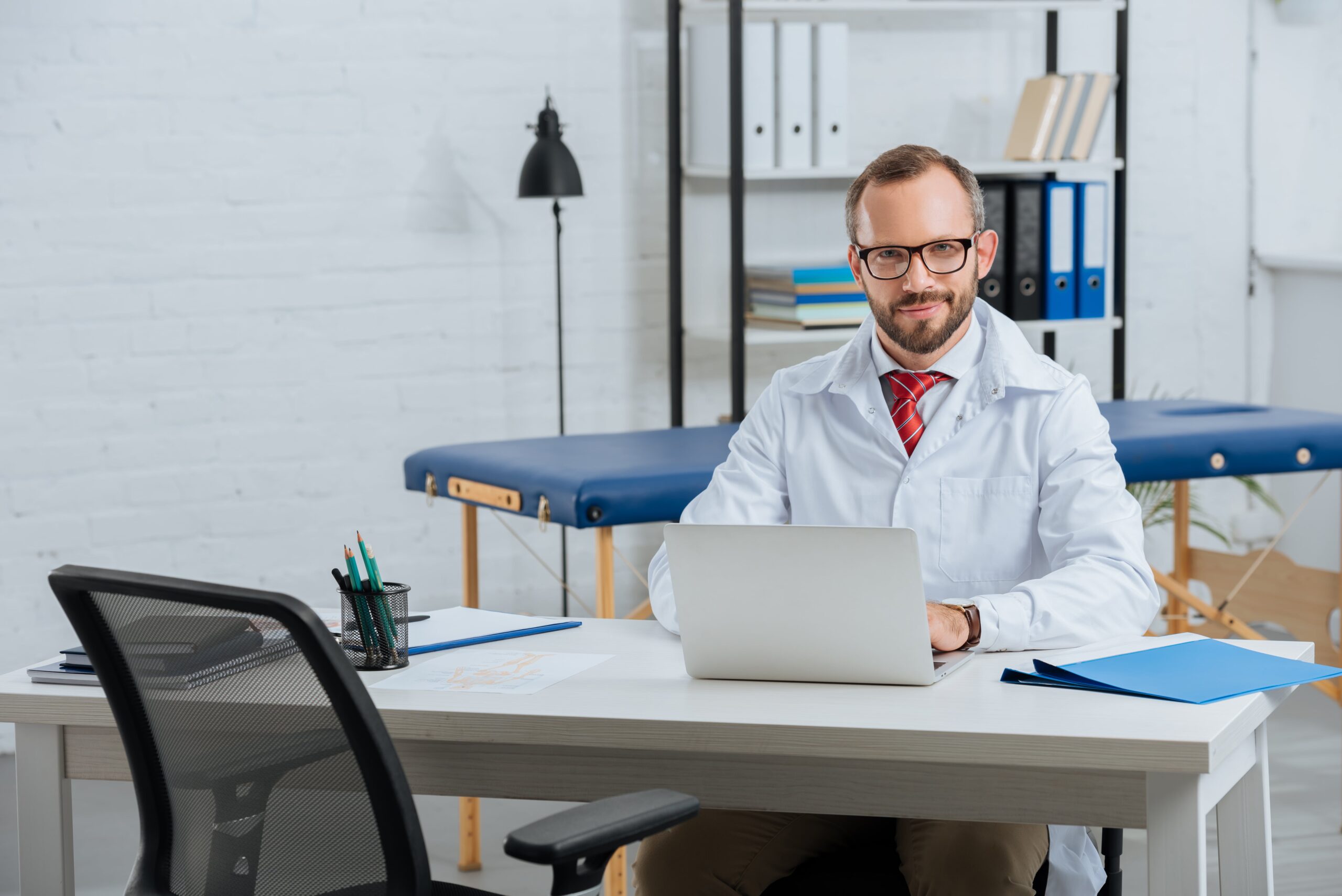 Portrait of smiling chiropractor using laptop.