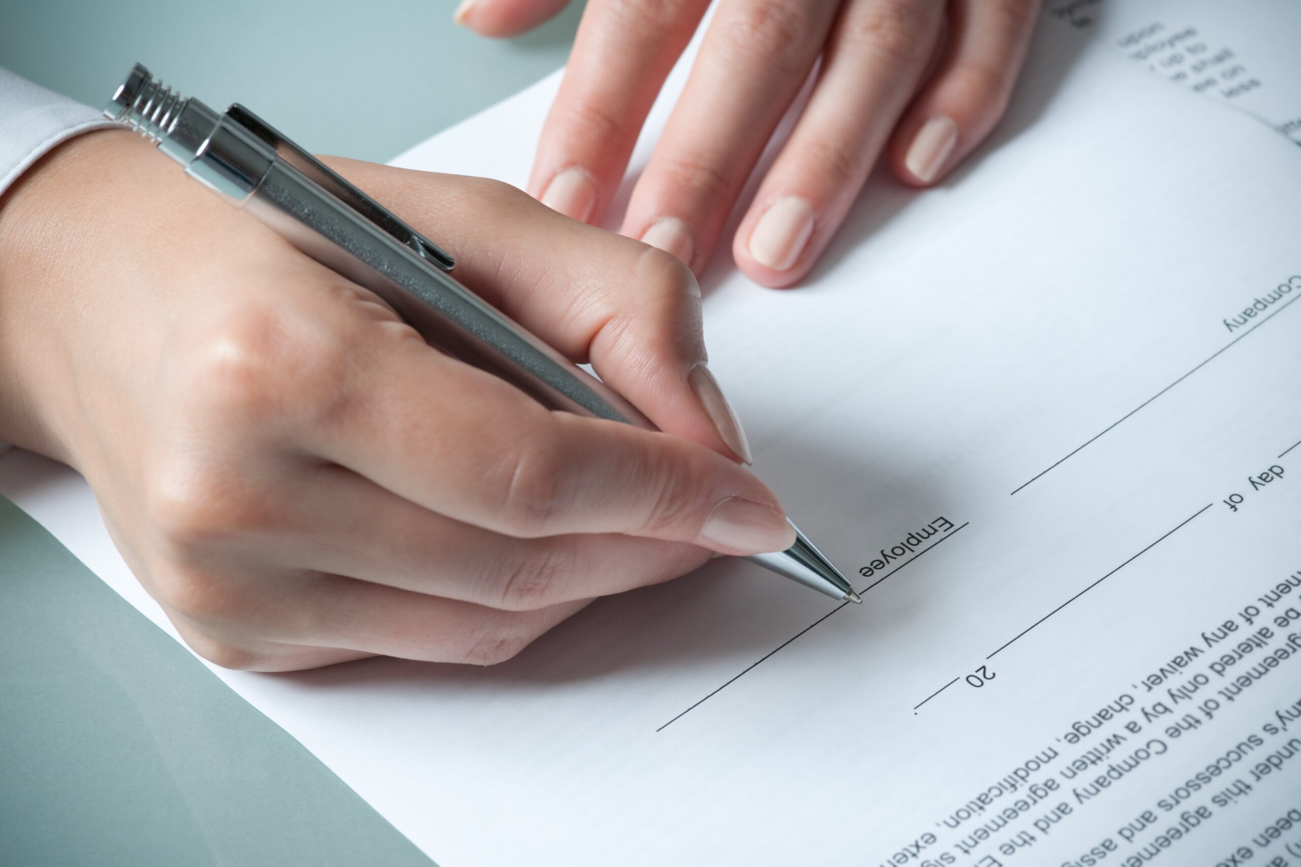 Closeup of person signing an employee agreement.